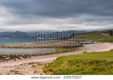 Laide, Scotland - June 8, 2012: The Rocky Beach At Laide Historic Cemetery Under Dark Rainy Cloudsca