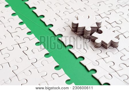 The Green Path Is Laid On The Platform Of A White Folded Jigsaw Puzzle. The Missing Elements Of The 