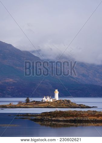 Famous Isle Ornsay With  Lighthouse Tower, Isle Of Skye, Scotland, Uk. Snowy Mountains In Background