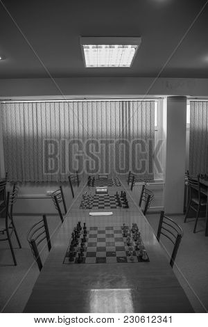Chess Club With Long Tables. Wooden Chess Board With Wooden Chess Pieces And Chess Clock.