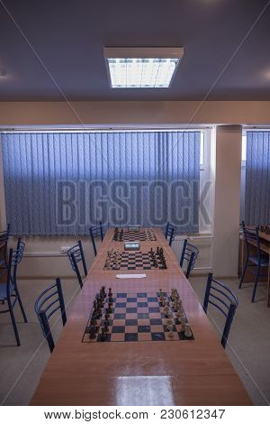 Chess Club With Long Tables. Wooden Chess Board With Wooden Chess Pieces And Chess Clock.
