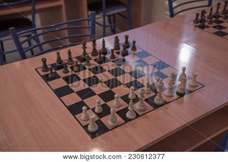 Chess Club With Long Tables. Wooden Chess Board With Wooden Chess Pieces And Chess Clock.