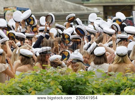 Stockholm, Sweden - Jun 13, 2017: Hands Holding Many Swedish White Graduation Caps, Green Trees In T
