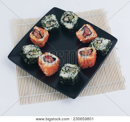 Different Types Of Maki Sushi On A Black Plate.isolated On White Background