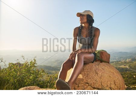 fit female hiker resting on top of mountain with view of san diego behind her