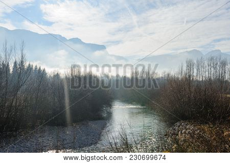Tree-filled River Banks Near The Town Of Echelles, In The French Savoy Eary, On A Dramatically Cloud