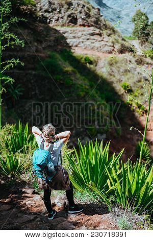 Woman With Camera And Backpack In Front Of The Arid Fins Of Rocks On Santo Antao Island, Cabo Verde.