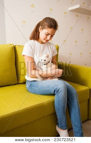 The Cat Is Protected In The Girl Hugs. They Are Sitting On The Green Sofa.