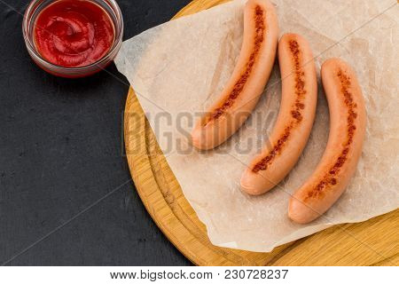 Grilled Sausages With Sauce Ketchup On A Wooden Board.