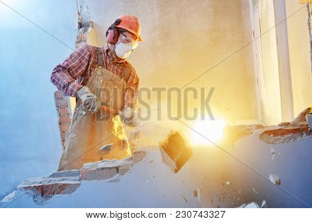 worker with sledgehammer at indoor wall destroying