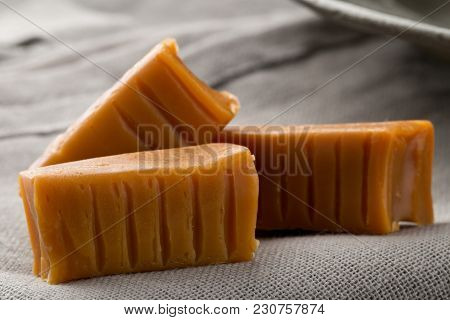 Hand Made Caramel Toffee Pieces On Grey Background On Kitchen Table