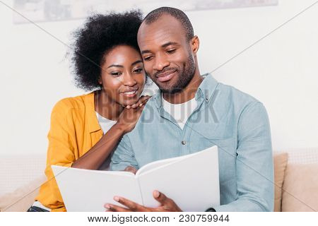 African American Couple Reading Book Together At Home