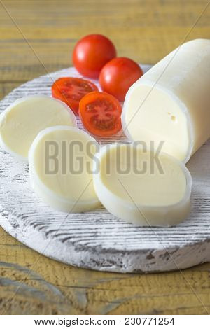Sliced Formaggio With Cherry Tomatoes On The Wooden Board