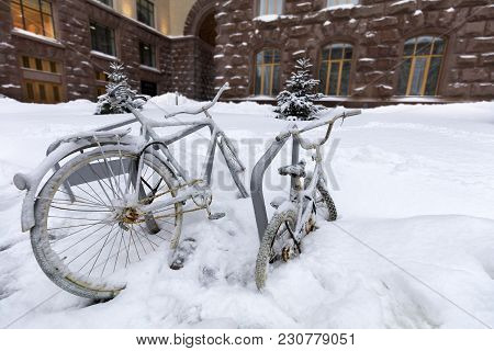 Two Bicycles Adult And Child Chained To The Counter Outside, Covered With Snow During The Snow