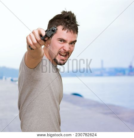 furious man pointing with gun at a port