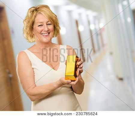 Happy Woman Holding Goldbar, Indoors