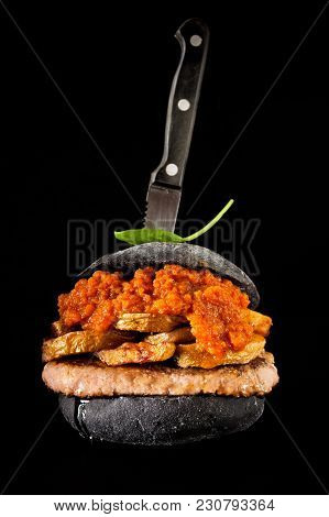 Italian Black Burger With Sausages Salamella , Potato And Vegetable Sauce. Stabbed The Knife