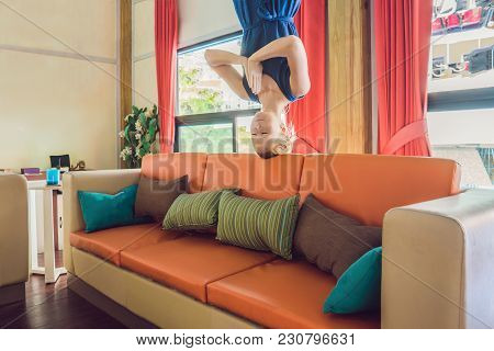A Woman Stands Upside Down In The Living Room And Meditates.