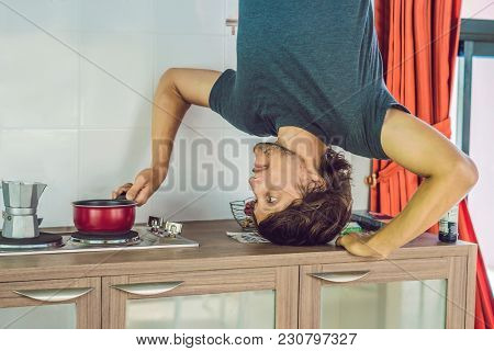A Man Stands On His Hands Upside Down In The Kitchen.