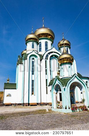 White church with gold domes a part of the European architecture. Russian orthodox church with typical golden onion domes