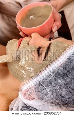 Collagen face mask. Facial skin treatment. Face of woman of elderly woman 50-60 years old receiving cosmetic procedure in beauty salon close up. Professional cosmetologist. Removal of pigmented spots.