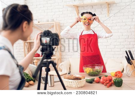 Two Culinary Bloggers In Red Aprons Mixing Diced Peppers With Salad To Camera.