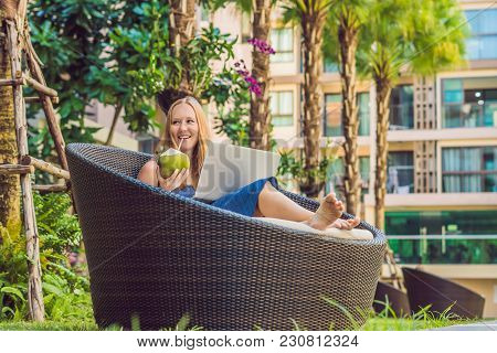 Young Female Freelancer Sitting Near The Pool With Her Laptop In The Hotel Browsing In Her Smartphon