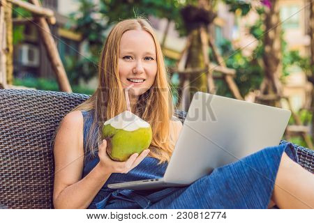 Young Female Freelancer Sitting Near The Pool With Her Laptop In The Hotel Browsing In Her Smartphon