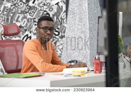 Young Black Man In The Office Behind His Desk.