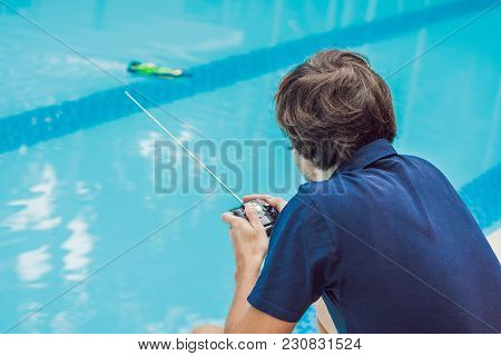 Man Playing With A Remote Controlled Boat In The Pool.