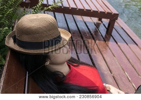 Asian Girl In The Resort In Red Clothes And Hat Sleep On Bed Pool., Background Of A Beautiful River.
