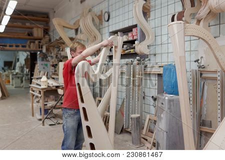 ST. PETERSBURG, RUSSIA - AUGUST 8, 2017: Worker making harp in Resonance Harps enterprise. The company revives the production of harps of the Lunacharsky factory founded in 1947
