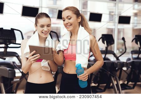 Mother And Daughter In Sportswear Using Tablet At The Gym. They Look Happy, Fashionable And Fit.