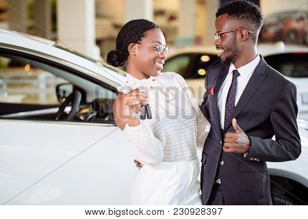 Young African Couple With Car Keys On Car Showroom Background