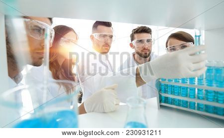 background image is a group of microbiologists studying the liqu
