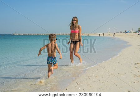 Happy Family Relaxing By The Sea. Happy Family Resting At Beach In Summer. Mother With Baby Boy Rest
