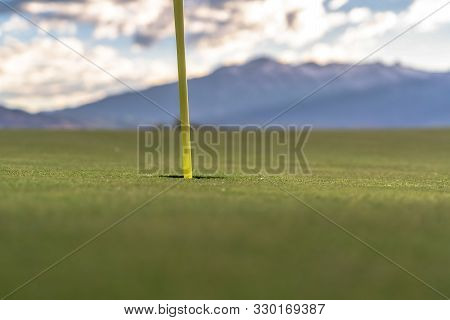 Focus On Golf Course Yellow Flagstick And Hole In The Middle Of Putting Green