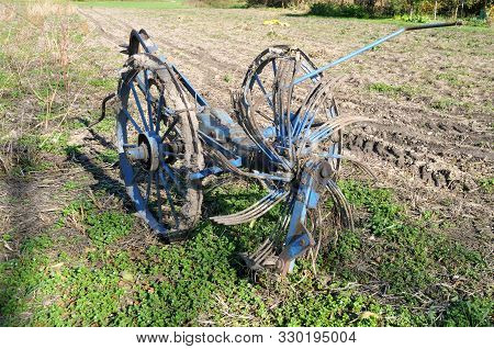 Old Nostalgic Hay Tedder With Flaking Blue Paint And Rusty Left On Field