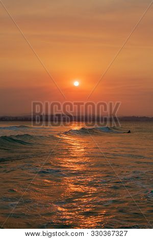 Surfer Goes Out To Enjoy The Waves During Sunset At Snapper Rocks, Queensland, Australia.
