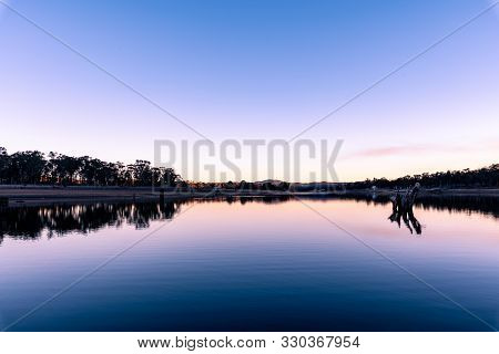 Reflection During Winter Sunset Over Dam On A Clear Day In Storm King, Queensland, Australia.