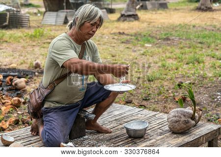 Ko Samui Island, Thailand - March 18, 2019: Gray Haired Man Squeezes Manually Remaining Juice Out Of