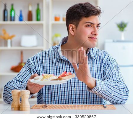 Young husband eating tasteless food at home for lunch