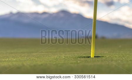 Panorama Focus On Golf Course Yellow Flagstick And Hole In The Middle Of Putting Green