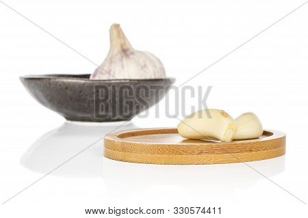 Group Of One Whole Two Pieces Of Aromatic White Garlic On Round Bamboo Coaster On Glazed Bowl Isolat