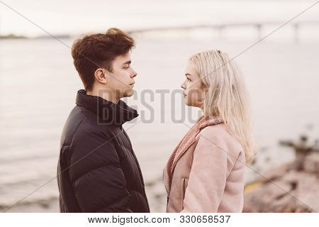 Lovely Brunette Guy And Pretty Girl Blonde Look At Each Other In Eyes, In Love Look. Loving Teenager