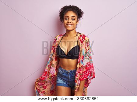 Young beautiful african american woman on vacation standing wearing bikini and colorful caftan