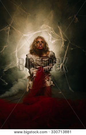 A Psycho In A Straitjacket Vomits On A Black Background In The Studio