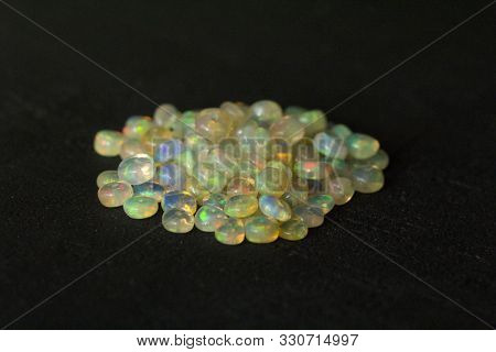 Opals Gemstone From Ethiopia Lies On Black Background. White Fire Opals With Rainbowlike Fire. Natur