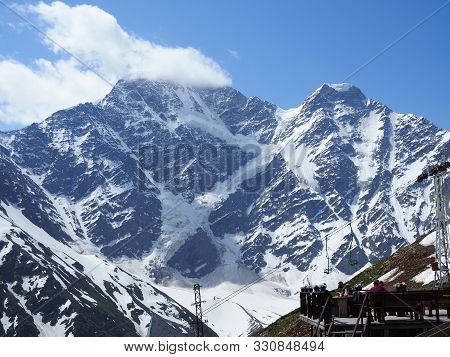 Tourists Sit In A Cafe High In The Mountains And Admire The Beautiful Views Of The Mountains. Beauti