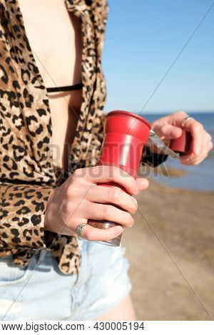 Red Manual Coffee Grinder In Female Hands Close Up. On Nature, Sea Background. Barista Girl